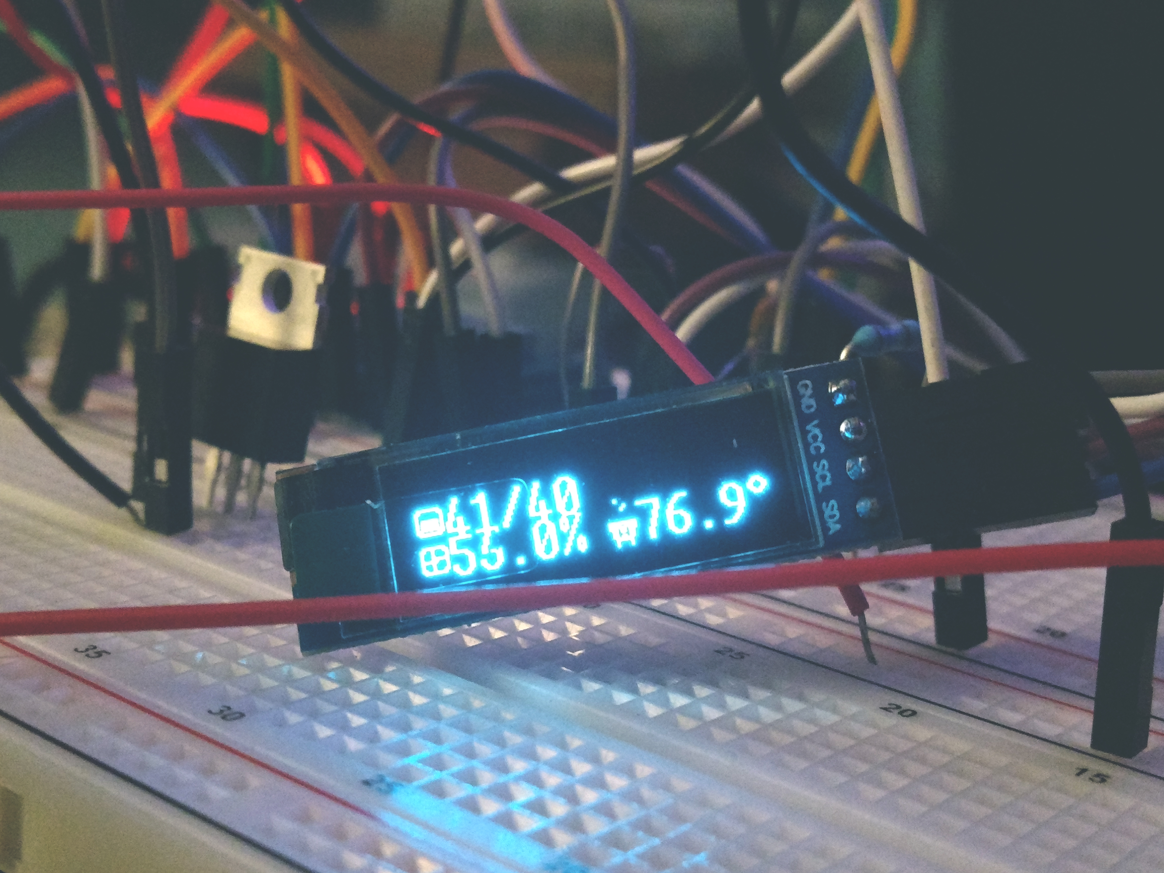 a small oled screen nestled into a tangle of breadboard wires, TO-220 mosfets are visible in the background