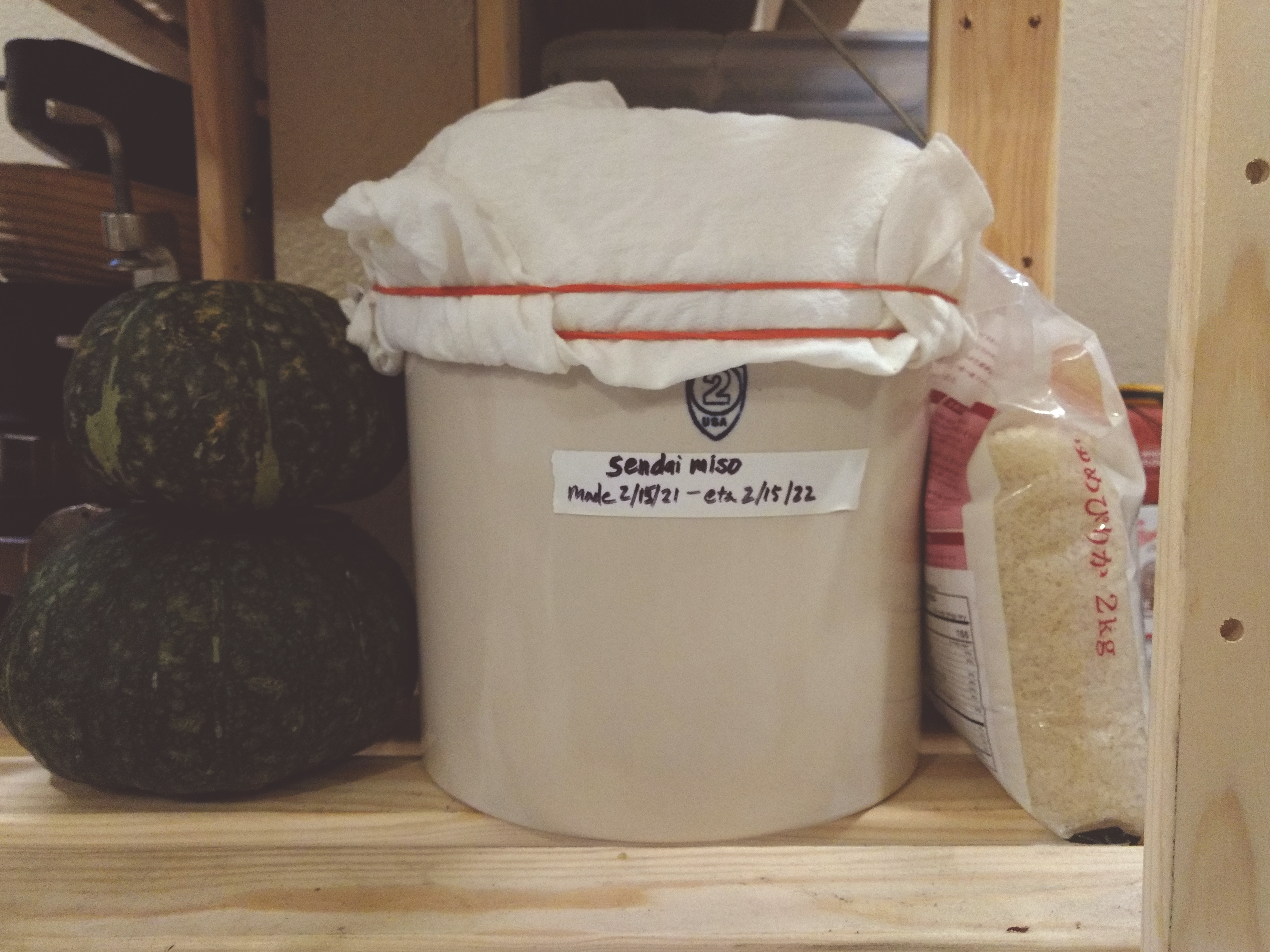 a crock with a label that reads 'sendai miso made 2/15/21 - eta 2/15/22'